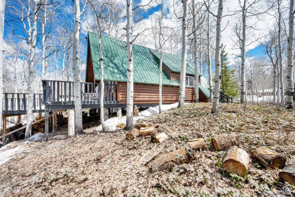 View of property exterior with log veneer siding, a deck, and metal roof