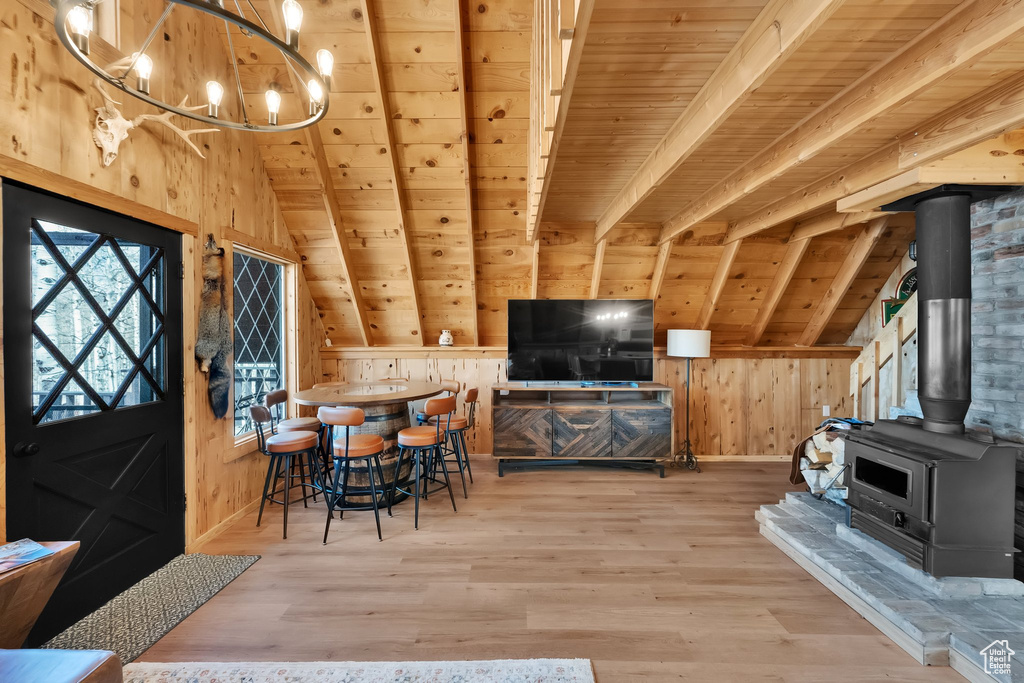 Interior space with a wood stove, wood finished floors, wooden ceiling, lofted ceiling with beams, and wooden walls