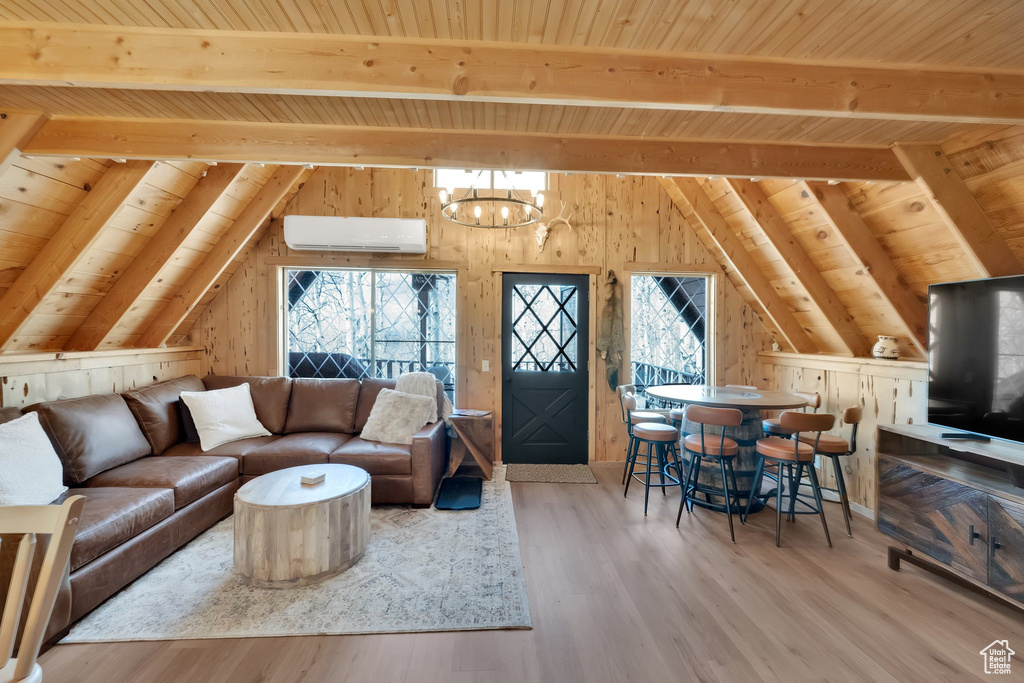 Living area featuring vaulted ceiling with beams, an AC wall unit, wooden ceiling, and a wealth of natural light