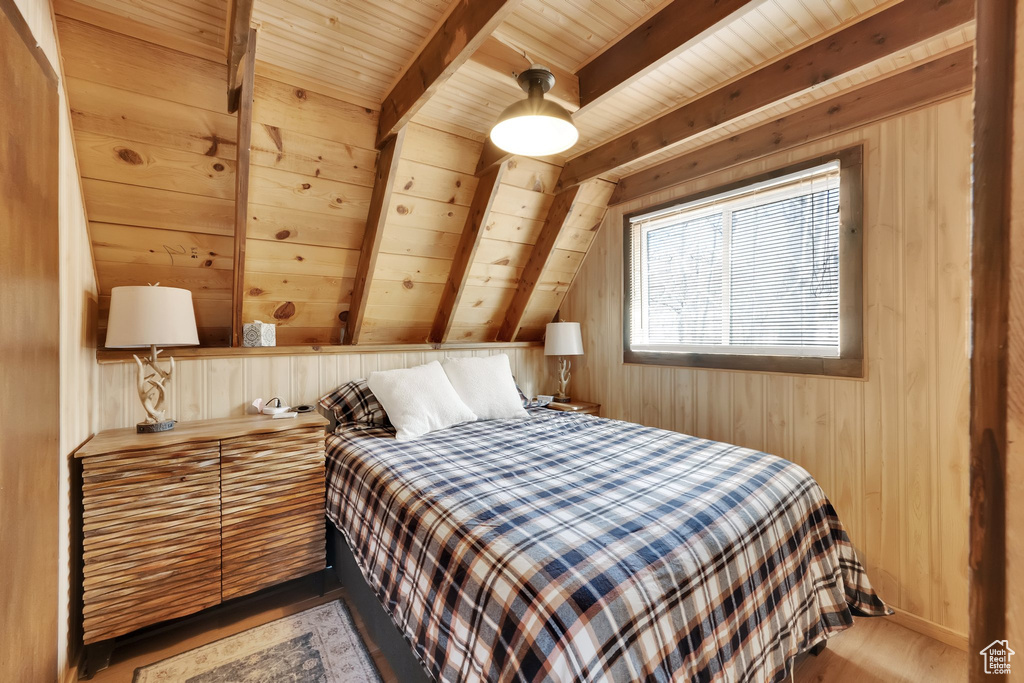 Bedroom featuring lofted ceiling with beams, wood ceiling, wood finished floors, and wooden walls
