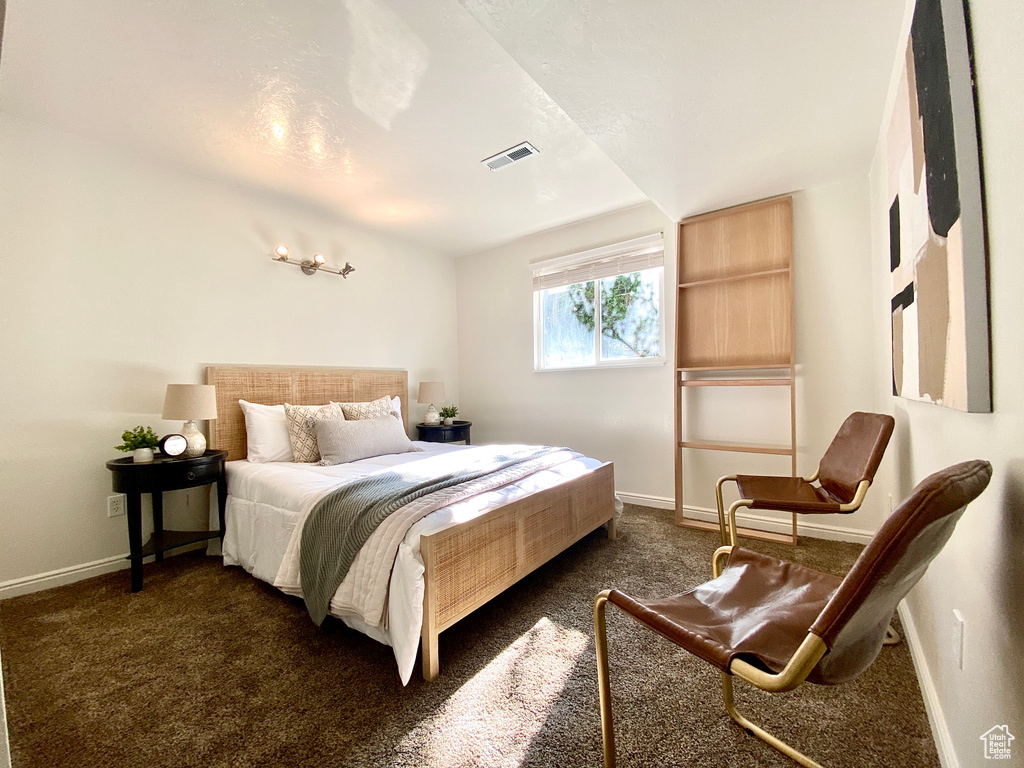 Bedroom featuring visible vents, baseboards, and dark colored carpet