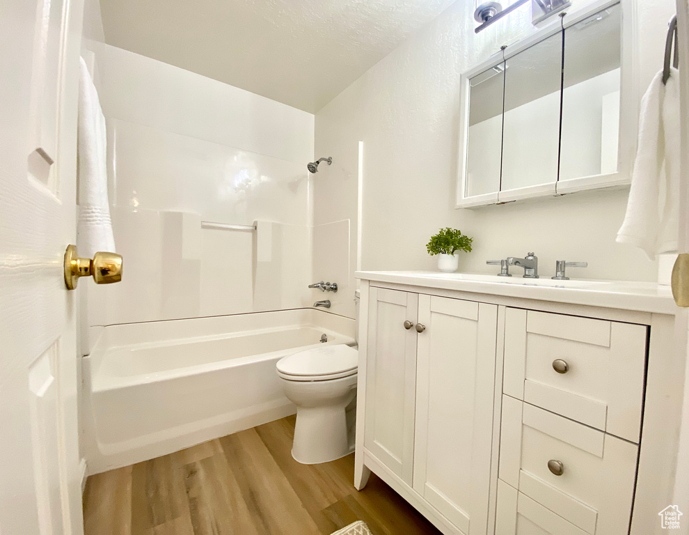 Bathroom with shower / bathtub combination, vanity, toilet, and wood finished floors