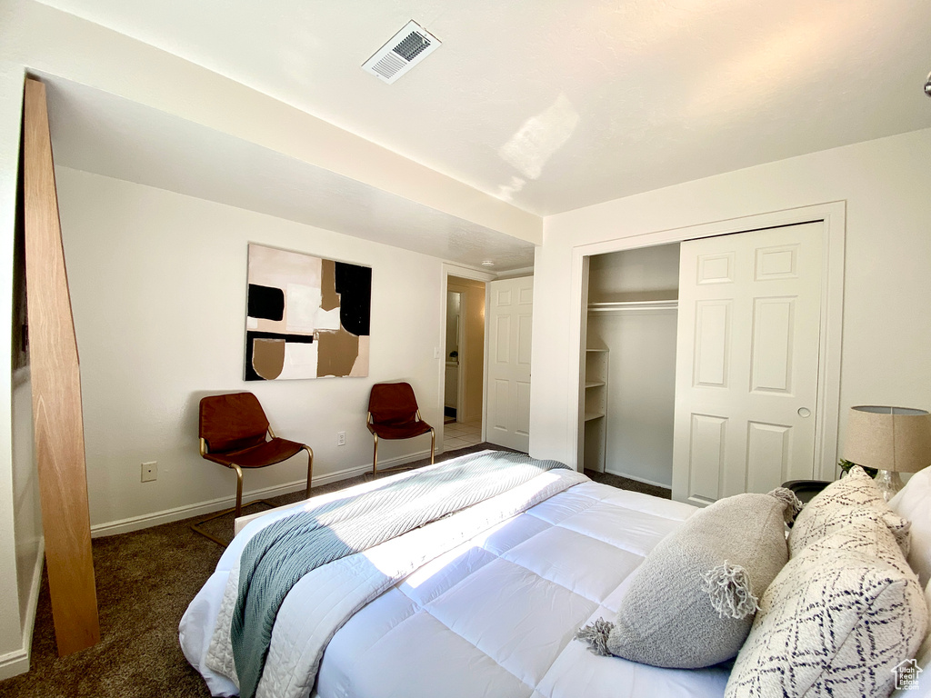 Carpeted bedroom featuring visible vents, baseboards, and a closet