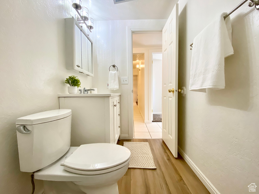 Bathroom featuring vanity, baseboards, toilet, and wood finished floors