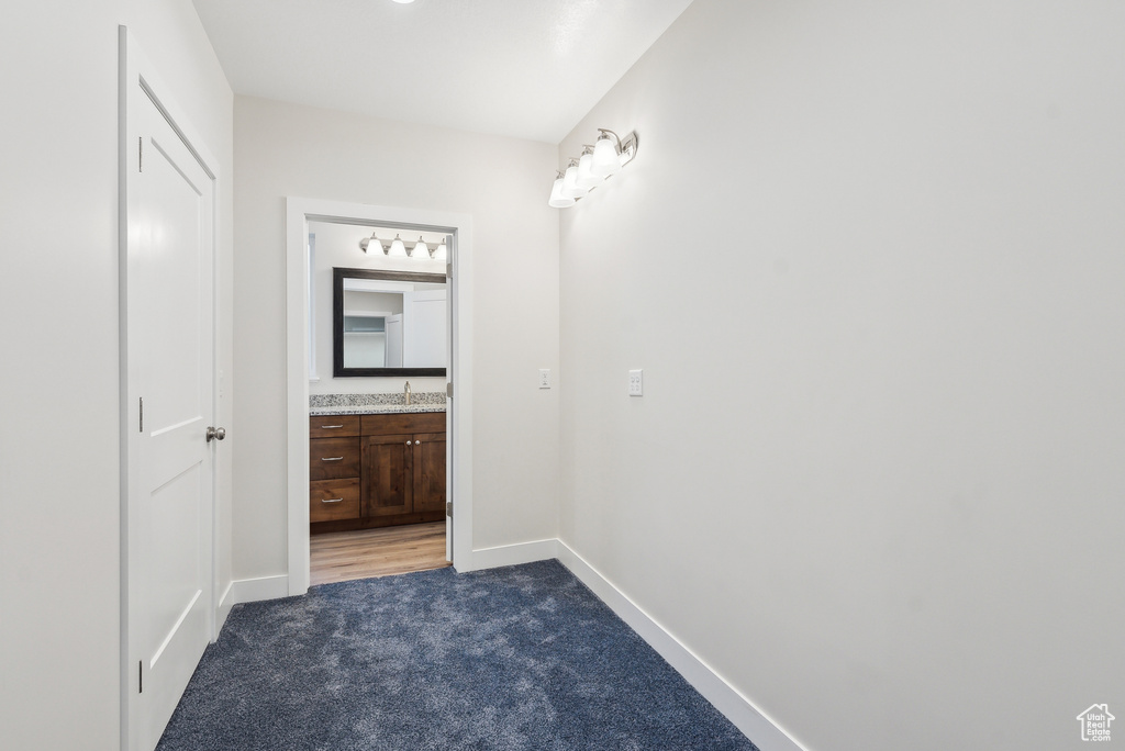 Hallway featuring a sink, baseboards, and carpet