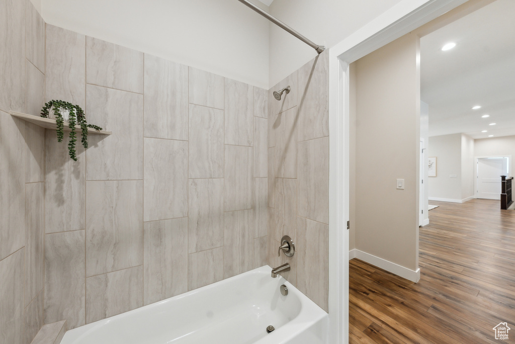 Bathroom featuring recessed lighting, baseboards, tub / shower combination, and wood finished floors
