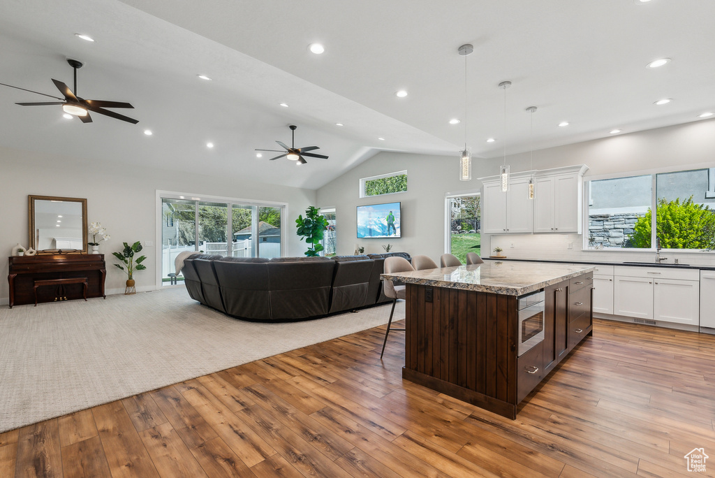 Kitchen with open floor plan, hardwood / wood-style flooring, white cabinetry, and ceiling fan