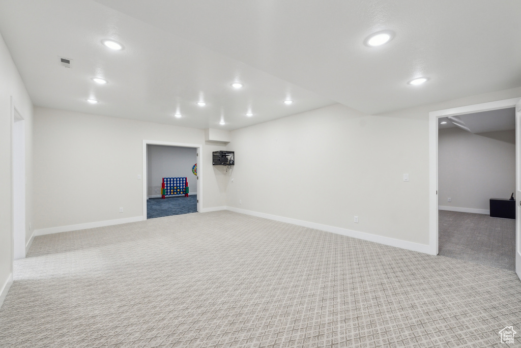 Finished below grade area with visible vents, baseboards, recessed lighting, and carpet