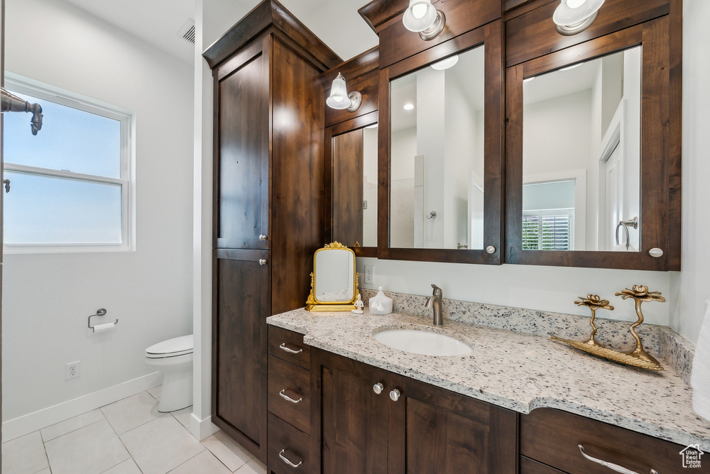 Bathroom featuring vanity, baseboards, toilet, and a healthy amount of sunlight