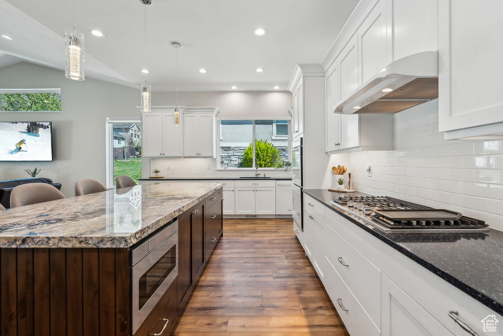 Kitchen featuring under cabinet range hood, wood finished floors, appliances with stainless steel finishes, and recessed lighting