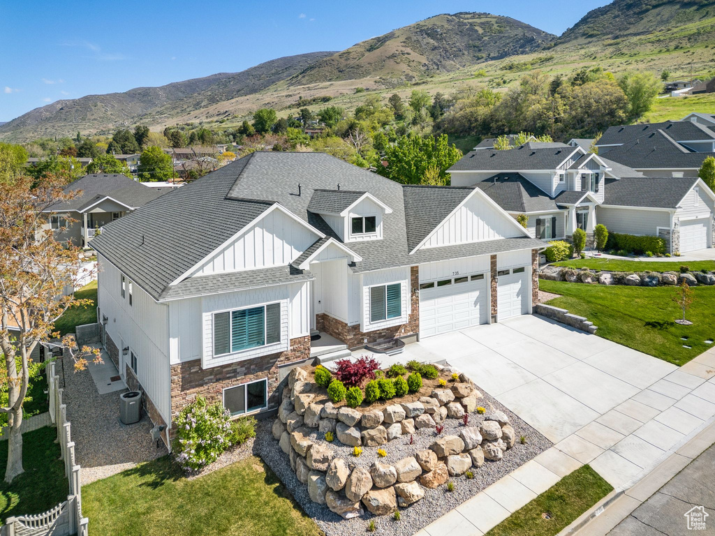 Modern farmhouse style home featuring an attached garage, stone siding, board and batten siding, a mountain view, and concrete driveway