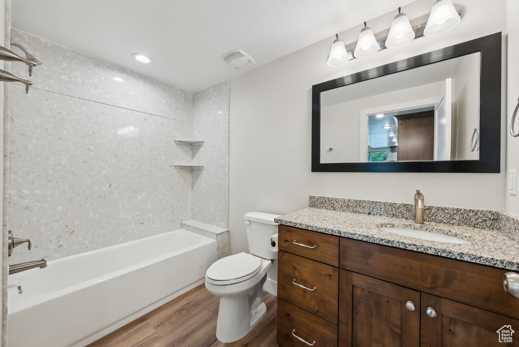 Bathroom with washtub / shower combination, vanity, toilet, visible vents, and wood finished floors