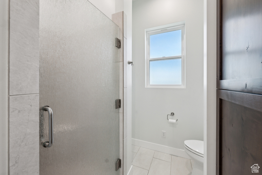 Full bath with a shower stall, baseboards, and toilet