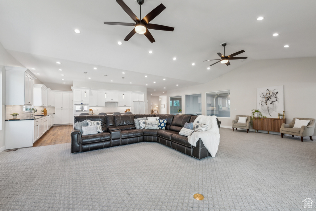 Living room featuring ceiling fan, recessed lighting, high vaulted ceiling, and light carpet
