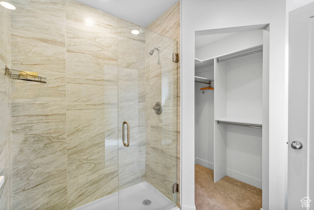 Bathroom featuring baseboards, a shower stall, and a spacious closet