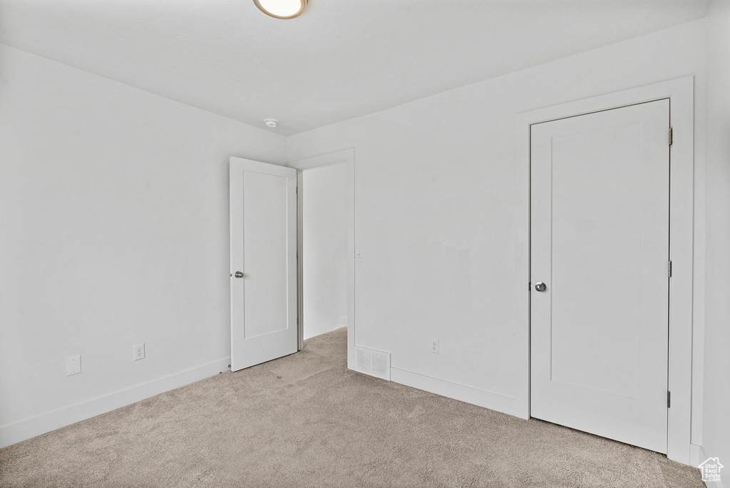 Spare room with baseboards, visible vents, and light carpet