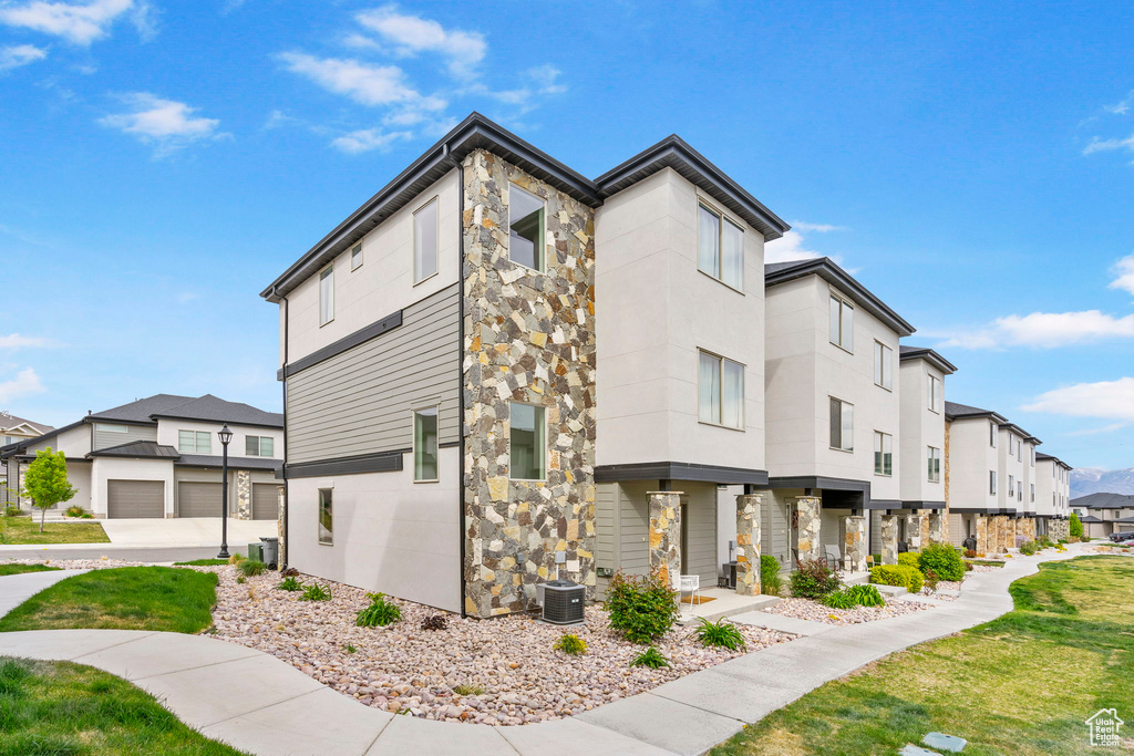 Exterior space with central air condition unit, a yard, a residential view, and stone siding