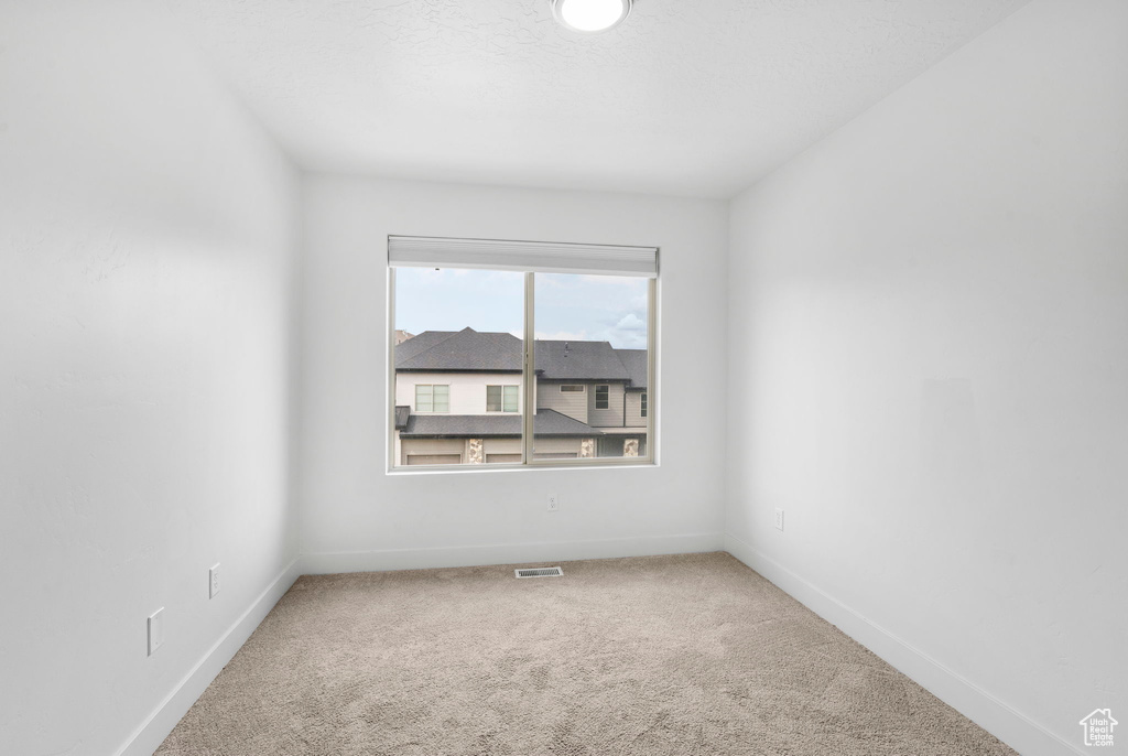 Empty room featuring visible vents, carpet flooring, and baseboards