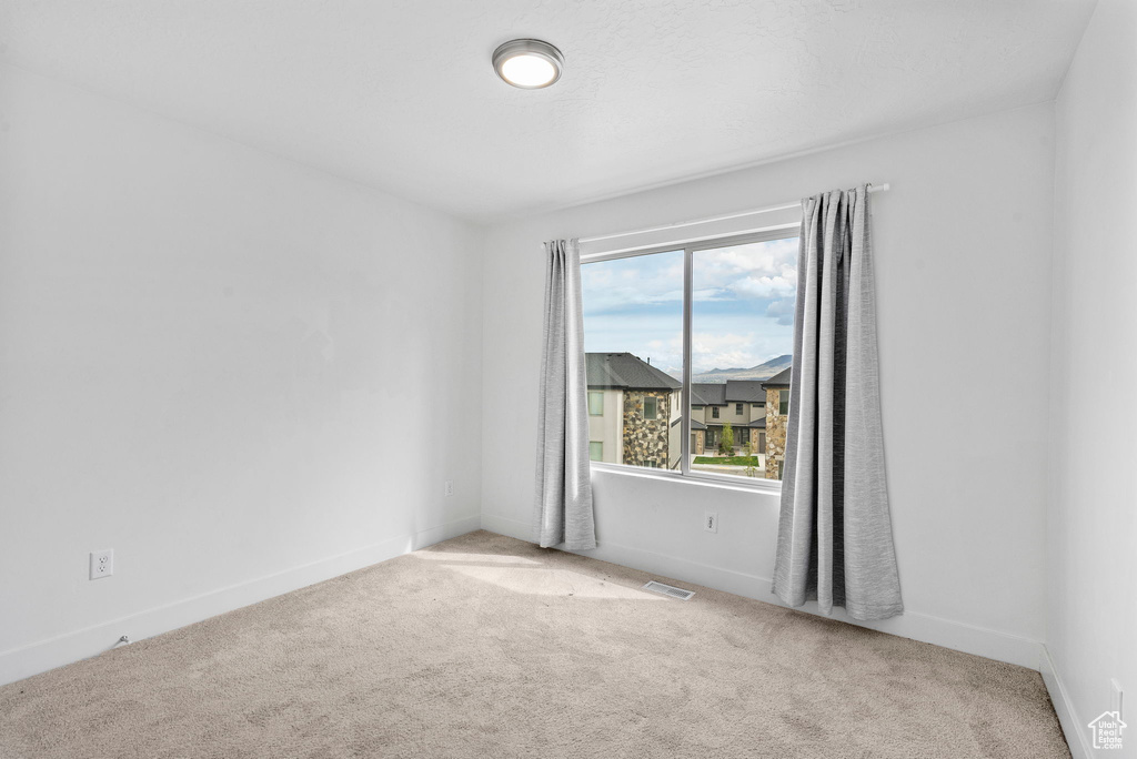 Empty room featuring visible vents, baseboards, and carpet floors