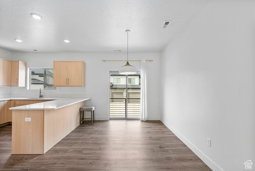 Kitchen with a peninsula, dark wood finished floors, visible vents, and light brown cabinets