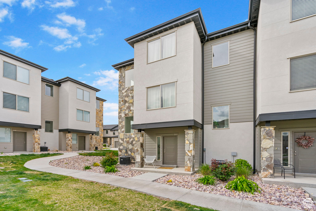 View of front of home featuring a residential view, stucco siding, central AC, and stone siding
