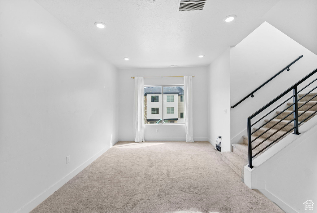 Carpeted entryway with recessed lighting, baseboards, visible vents, and stairway