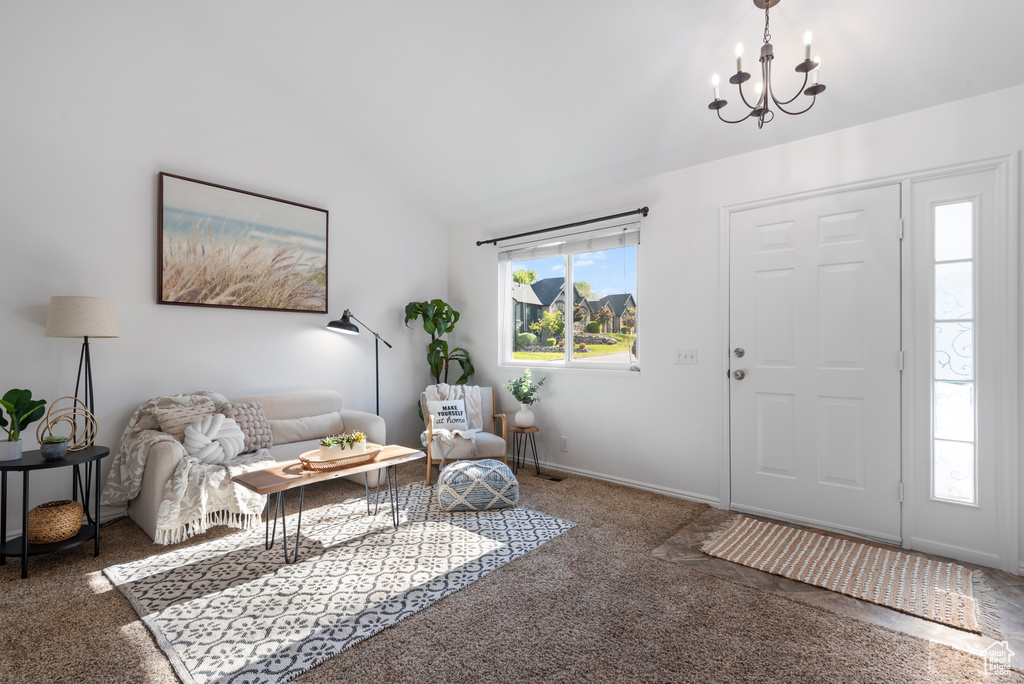 Foyer entrance featuring an inviting chandelier, carpet, and vaulted ceiling