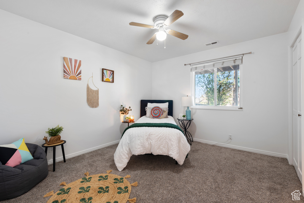 Carpeted bedroom featuring baseboards, visible vents, and ceiling fan