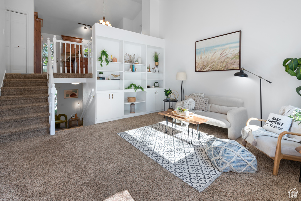 Carpeted living room with high vaulted ceiling and stairway