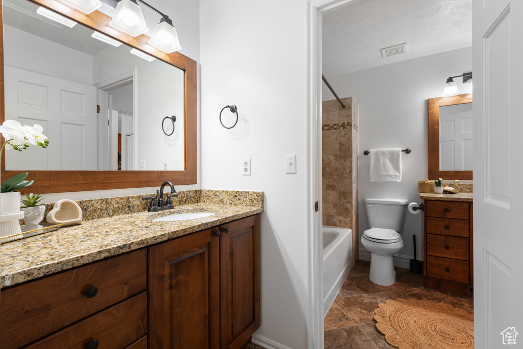 Full bathroom with shower / washtub combination, vanity, toilet, and visible vents