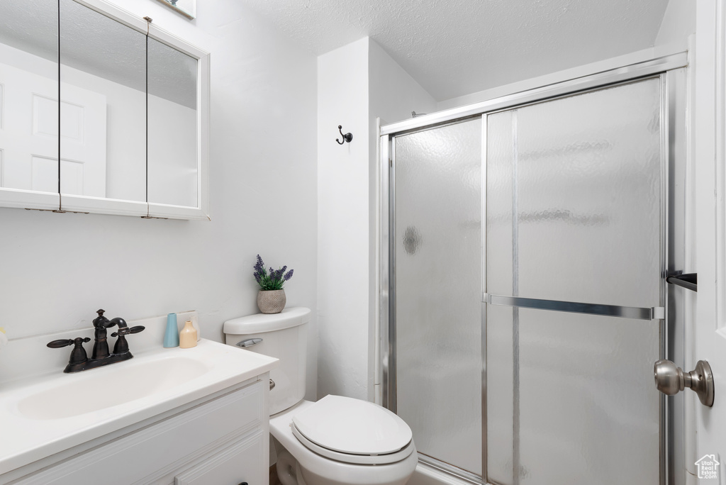 Full bath featuring vanity, a textured ceiling, a stall shower, and toilet
