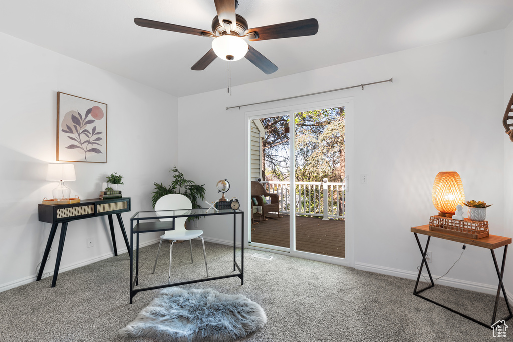 Carpeted office space with a ceiling fan and baseboards