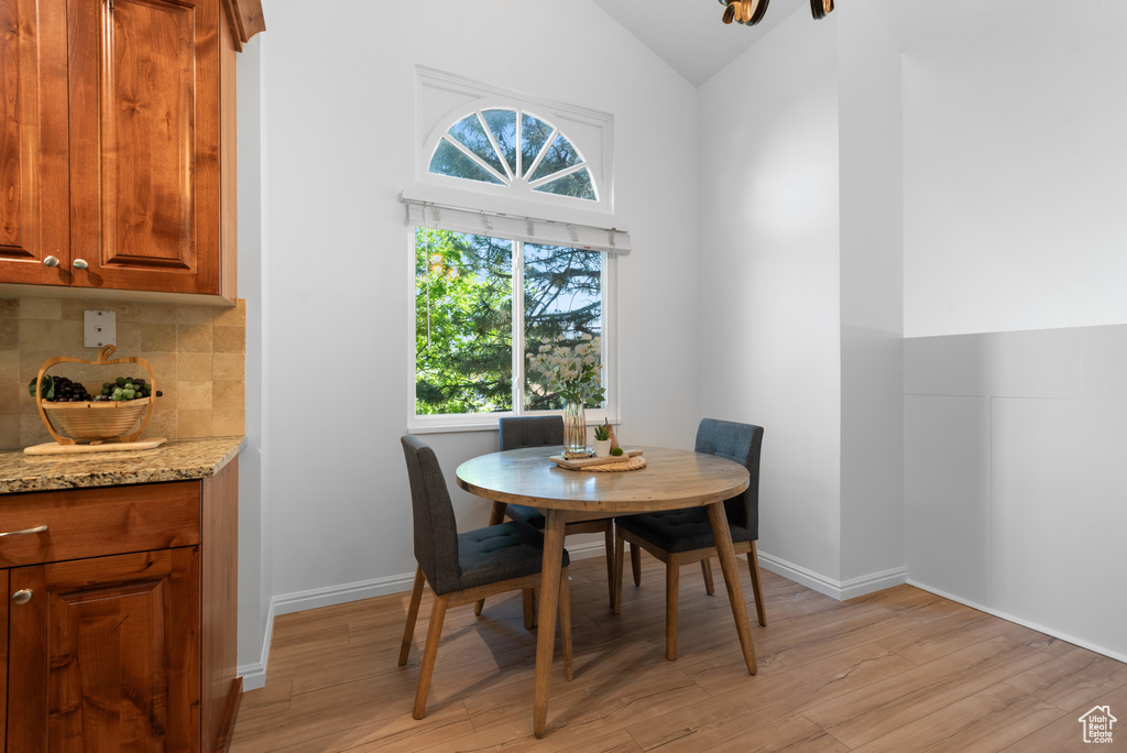Dining area featuring baseboards, lofted ceiling, and light wood finished floors