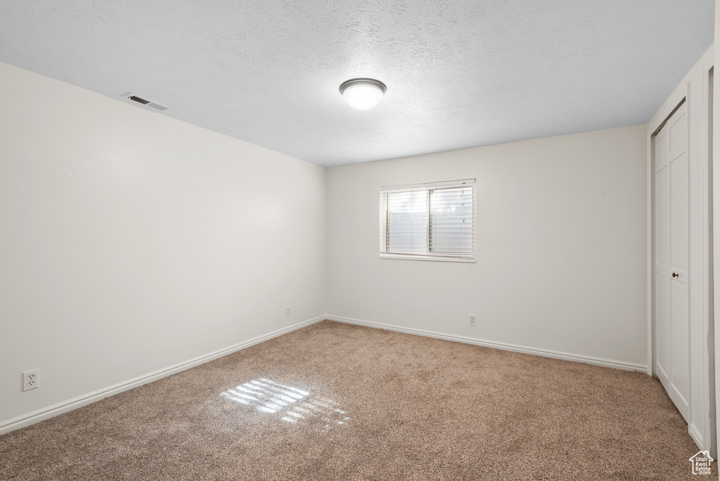 Unfurnished bedroom with baseboards, carpet, a closet, and visible vents