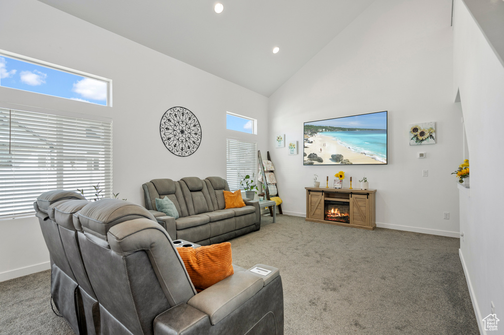 Carpeted living room featuring a warm lit fireplace, recessed lighting, high vaulted ceiling, and baseboards