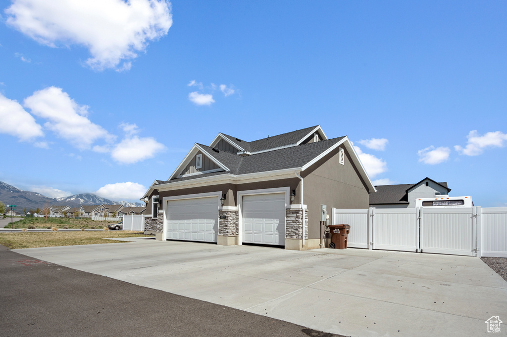 View of side of home featuring fence, stucco siding, a gate, a mountain view, and concrete driveway