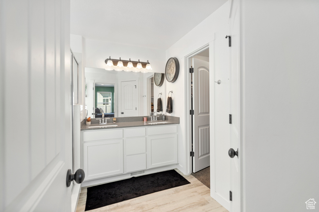 Bathroom featuring double vanity, a sink, and wood finished floors
