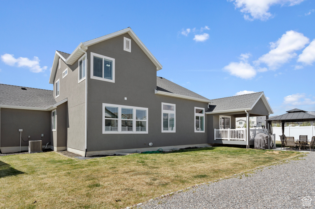 Rear view of house with a lawn, a gazebo, and stucco siding
