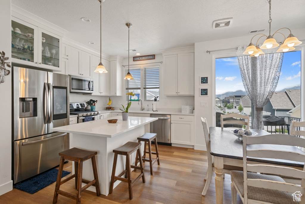 Kitchen featuring appliances with stainless steel finishes, a sink, a chandelier, light wood-type flooring, and light countertops