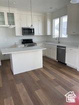 Kitchen featuring stainless steel microwave, dishwasher, range, a center island, and light countertops
