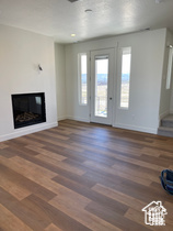 Unfurnished living room with baseboards, wood finished floors, and a glass covered fireplace