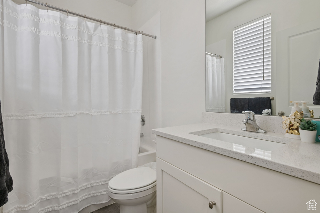 Bathroom with toilet, vanity, and shower / tub combo with curtain