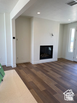 Unfurnished living room featuring a glass covered fireplace, baseboards, wood finished floors, and recessed lighting