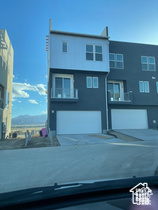 View of front facade featuring an attached garage, driveway, and stucco siding