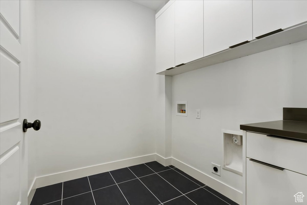Laundry room featuring baseboards, hookup for a washing machine, cabinet space, and dark tile patterned flooring