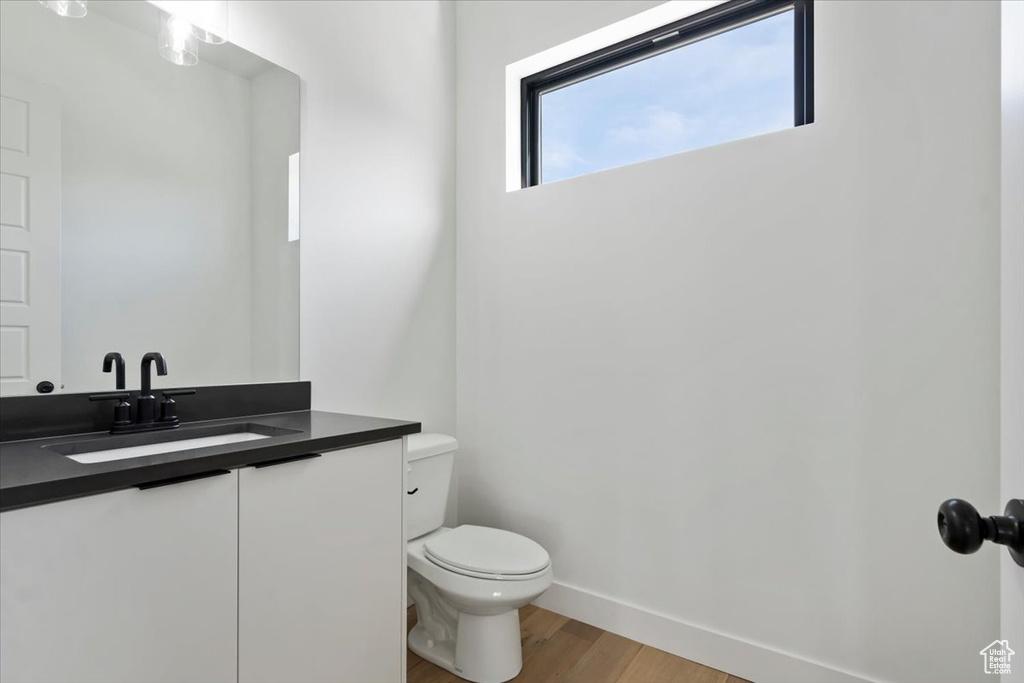 Bathroom with toilet, baseboards, wood finished floors, and vanity