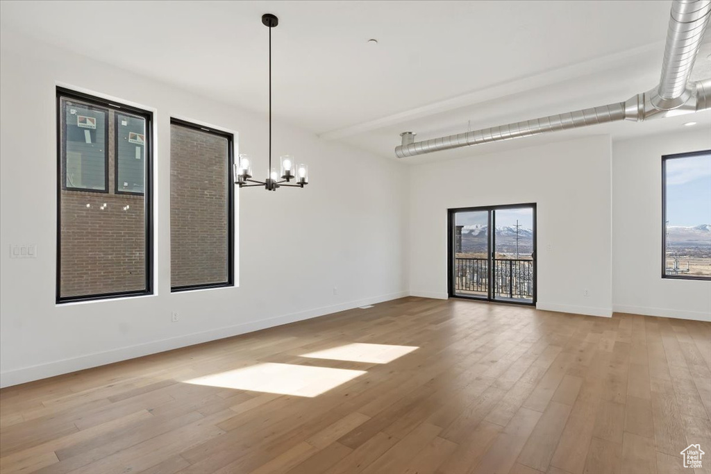 Unfurnished dining area featuring an inviting chandelier, baseboards, and wood finished floors
