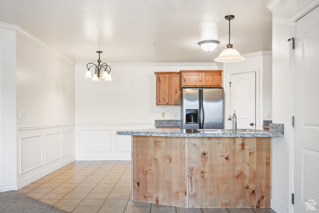 Kitchen featuring a peninsula, light tile patterned flooring, stainless steel refrigerator with ice dispenser, a sink, and a notable chandelier