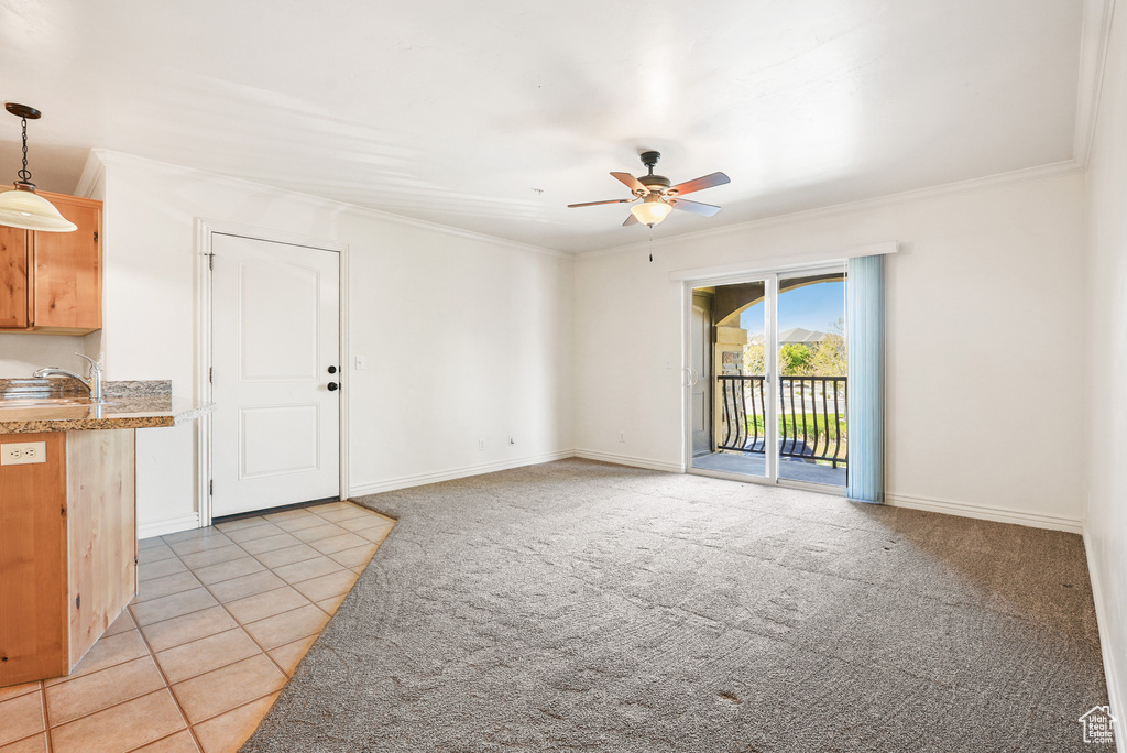 Unfurnished living room with ceiling fan, baseboards, ornamental molding, light carpet, and light tile patterned flooring