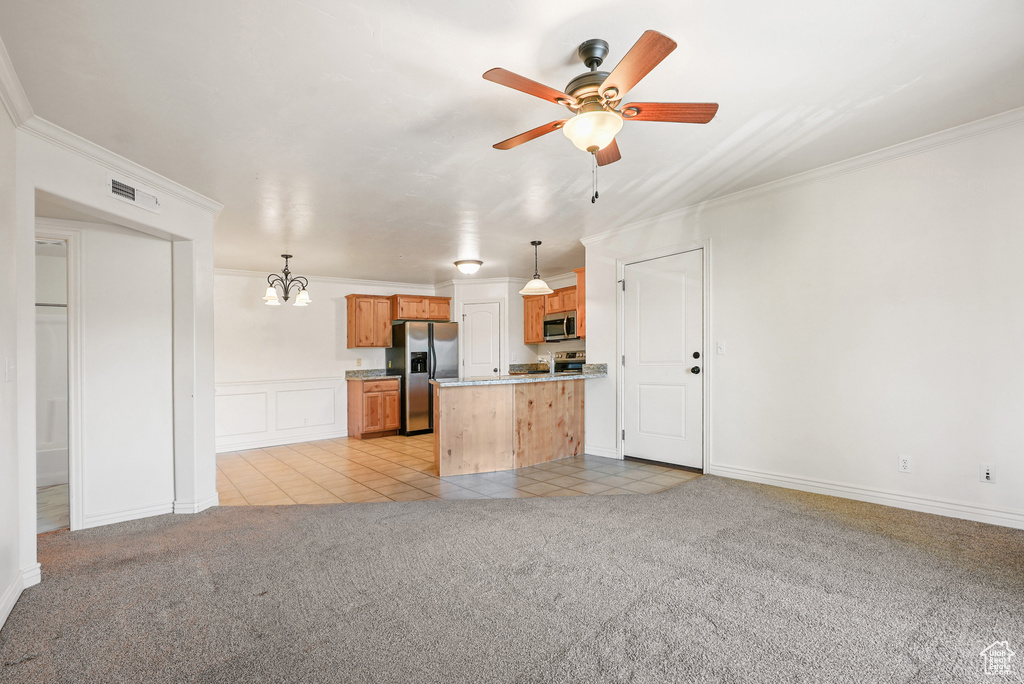 Kitchen featuring light colored carpet, appliances with stainless steel finishes, ceiling fan with notable chandelier, light tile patterned floors, and ornamental molding